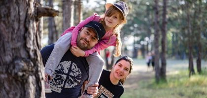 A joyful family enjoying a playful day in a sunlit forest park, capturing the essence of togetherness.