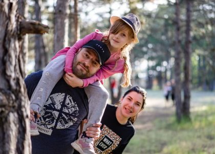 A joyful family enjoying a playful day in a sunlit forest park, capturing the essence of togetherness.