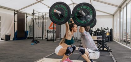 A couple lifting weights together in a gym, promoting fitness and teamwork.