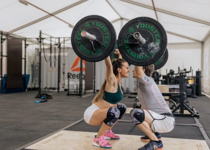 A couple lifting weights together in a gym, promoting fitness and teamwork.